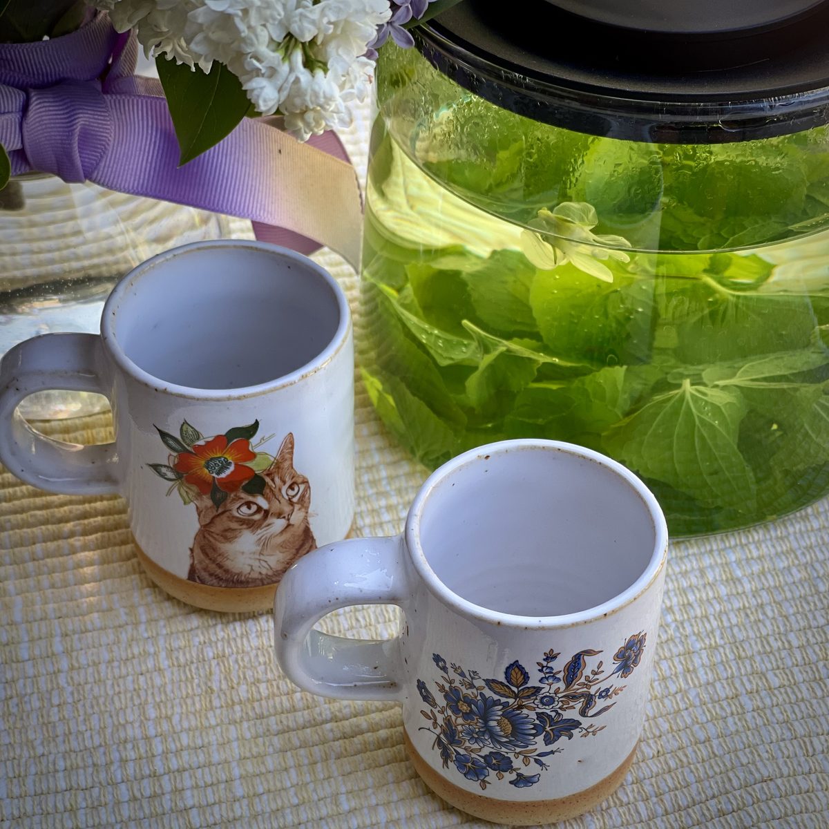 Two mugs beside a jar of fresh herbal tea